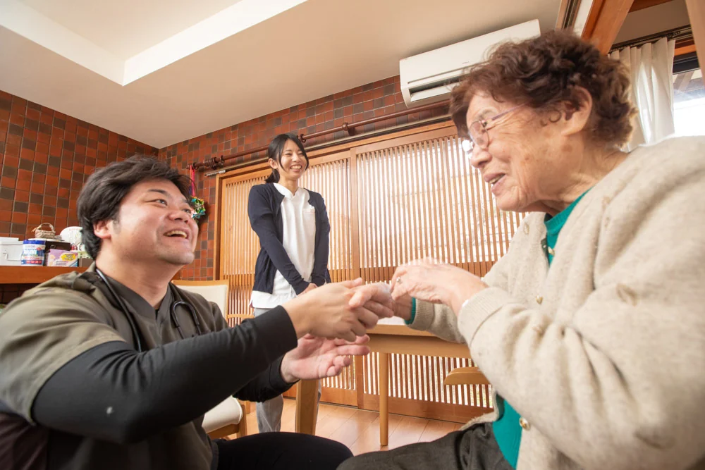 患者さんの手を取って話す院長とスタッフ